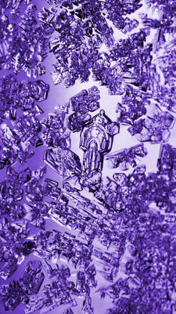 Ice crystals close-up on a window glass in winter. Tinted purple vertical background or mobile wallpaper. frozen water. Violet mystical fabulous abstract pattern. Strong macroの写真素材