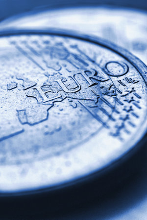 euro coins. The focus is on the inscription with the name of the Euro Zone currency on the 1 euro coin. closeup. Blue tinted vertical illustration about the economy and money of the European Union. Macroの写真素材