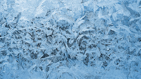 Pattern of ice on a window pane in winter. Spectacular drawing of crystals of frozen water. It looks...