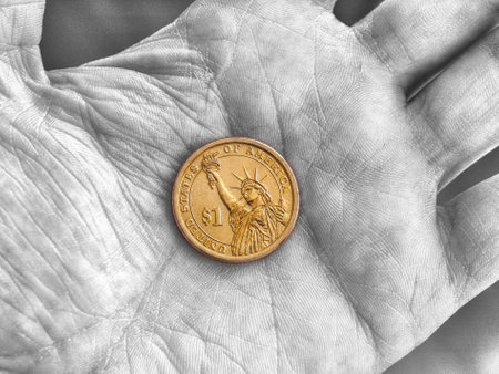 American 1 one dollar coin lies on a dirty palm close up. An impressive, dramatic black and white shot with an accentuated yellow coin. Low-wage labor, manual or unskilled work, poverty. Macroの写真素材