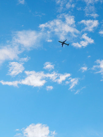 The passenger airplane is flying far away in the blue sky and white clouds. Aircraft in the air. international passenger air transport. vertical illustrationの写真素材