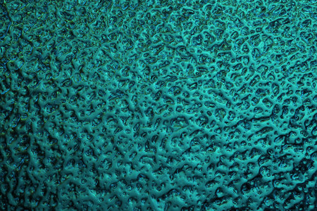 Bright teal winter background. The surface of ice frozen on the window pane. An abstract pattern with a metallic sheen, similar to the ripples of mercury. Rich turquoise wallpaper. close-upの写真素材