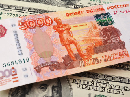 The Russian denomination of 5,000 rubles hangs over a field of American $ 100 banknotesの写真素材