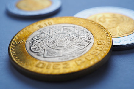 Mexican coins lie on blue surface. Coin of 10 ten pesos close-up. Peso of Mexico. News about economy or banking. Loan and credit. Wages and money. Macroの写真素材