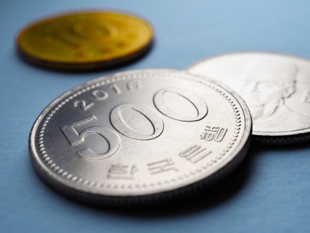 Translation: Bank of Korea. Korean coins lie on blue paper surface. 500 won coin close up. Illustration about economy, finance or bank. Money and business in South Korea. Macroの写真素材