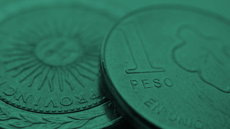 Coin of 1 Argentine peso close-up. One peso coins of Argentina. News about economy or currency. Loan and credit. Money and taxes. Focus on word pesos. Dark green tinted wallpaper. Macroの写真素材