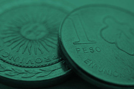 Coin of 1 Argentine peso closeup. One peso coins of Argentina. News about economy or banking. Loan and credit. finance and bank. Focus on word pesos. Dark green tinted background. Macroの写真素材