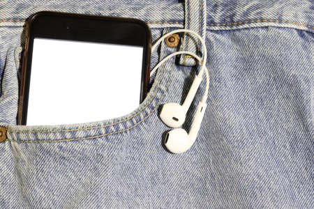 Phone and earphones with a blank white screen in a pocket of light jeans. Mock up.の写真素材