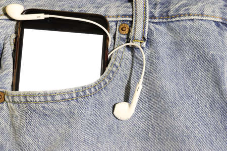 Phone and earphones with a blank white screen in a pocket of light jeans. Mock up.の写真素材