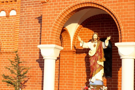 Monument of Jesus Christ against the background of a bright brick temple under the arch. Copy space for text. Religion and church service.の写真素材