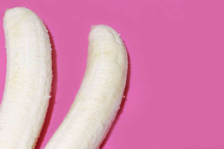 Two fully peeled bananas on a pink background top view. Flat lay with copy space for text.の写真素材