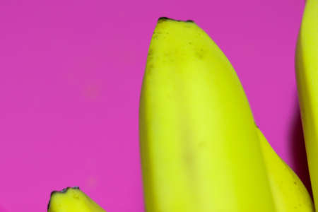 Bright yellow banana close-up on a bright pink or purple background top view. Copy space.の写真素材