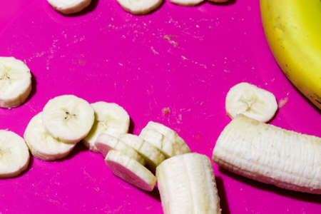 Sliced banana slices top view on pink or purple background. Copy space for text. Healthy eating and healthy lifestyle.の写真素材