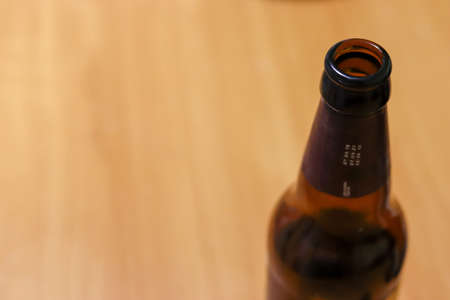 Empty beer bottle on a wooden table background. Copy space for text. Moderate alcohol consumption. Alcoholism and social problems. Blurred background.の写真素材