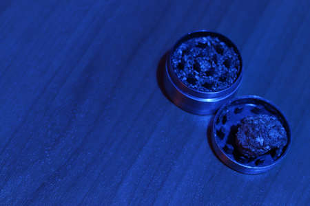 Close-up medical marijuana in a grinder on a table in blue lighting. Drug use for medical purposes. Copy space. Ground weed. Accessories for smoking.の写真素材
