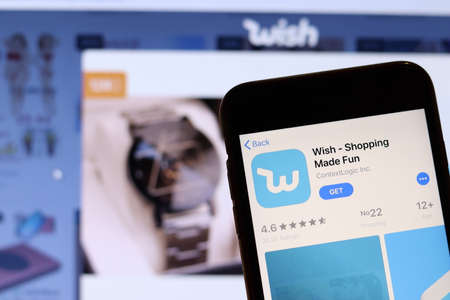 Los Angeles, California, USA - 27 November 2019: Wish app icon on mobile phone screen with blurry website on laptop, Illustrative Editorial.のeditorial素材