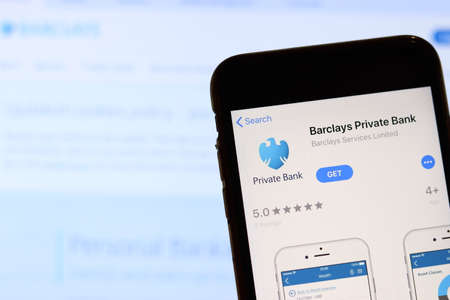 Los Angeles, California, USA - 27 November 2019: Barclays Private Bank app icon on mobile phone screen with blurry website on laptop, Illustrative Editorial.のeditorial素材