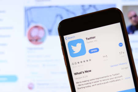 Phone with Twitter icon on screen close up with blur website on laptop. Los Angeles, California, USA - 30 November 2019, Illustrative Editorial.のeditorial素材