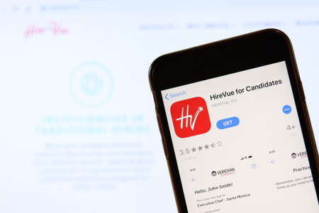Phone with HireVue icon on screen close up with blur website on laptop. Los Angeles, California, USA - 30 November 2019, Illustrative Editorial.のeditorial素材