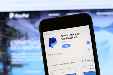 Phone with PayPal Business icon on screen close up with blur website on laptop. Los Angeles, California, USA - 30 November 2019, Illustrative Editorial.のeditorial素材