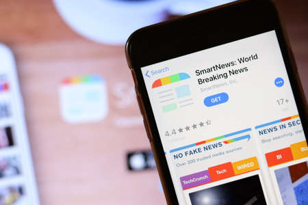 Phone with SmartNews app icon on screen close up with blur website on laptop. Los Angeles, California, USA - 30 November 2019, Illustrative Editorial.のeditorial素材
