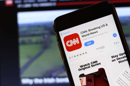 Phone with CNN app icon on screen close up with blur website on laptop. Los Angeles, California, USA - 30 November 2019, Illustrative Editorial.のeditorial素材