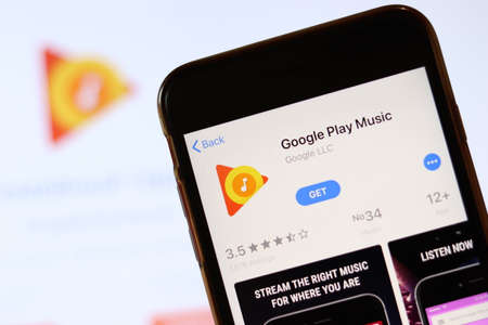 Phone with Google Play Music icon on screen close up with blur website on laptop. Los Angeles, California, USA - 30 November 2019, Illustrative Editorial.のeditorial素材