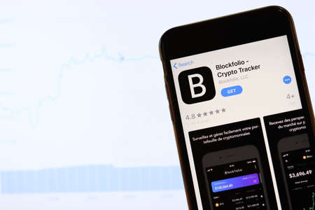 Phone with Blockfolio Crypto Tracker icon on screen close up with blur website on laptop. Los Angeles, California, USA - 30 November 2019, Illustrative Editorial.のeditorial素材
