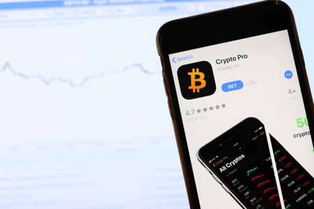 Phone with Crypto Pro icon on screen close up with blur website on laptop. Los Angeles, California, USA - 30 November 2019, Illustrative Editorial.のeditorial素材