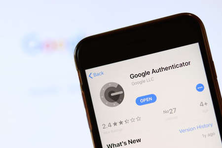 Phone with Google Authenticator icon on screen close up with blur website on laptop. Los Angeles, California, USA - 30 November 2019, Illustrative Editorial.のeditorial素材