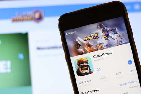 Phone with Clash Royale icon on screen close up with blur website on laptop. Los Angeles, California, USA - 30 November 2019, Illustrative Editorial.のeditorial素材
