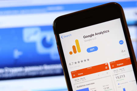 Phone with Google Analytics icon on screen close up with blur website on laptop. Los Angeles, California, USA - 30 November 2019, Illustrative Editorial.のeditorial素材