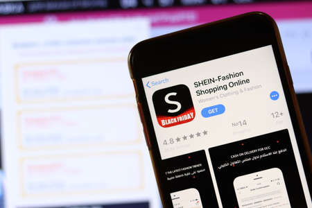Phone with SHEIN app icon on screen close up with blur website on laptop. Los Angeles, California, USA - 30 November 2019, Illustrative Editorial.のeditorial素材