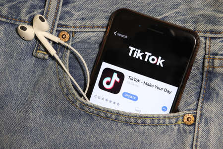 Los Angeles, California, USA - 5 December 2019: TikTok app icon on phone screen in blue jeans pocket with headphones. App Store logo on Iphone, denim background with earphones, Illustrative Editorial.のeditorial素材