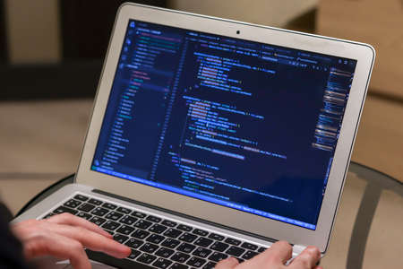 IT specialist working on laptop. Hands on keyboard. Programmer writing code.