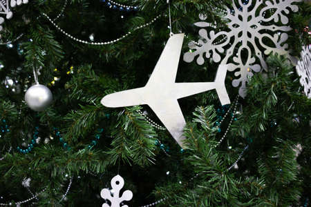 Toy airplane on the background of Christmas tree branches with Christmas balls and a snowflake. New Year Travel Concept.の写真素材