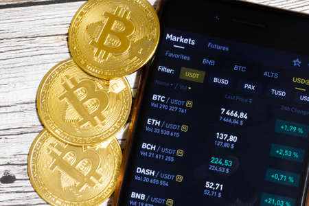 Cryptocurrency value, price chart on phone display. Bitcoin coins close-up top view.の写真素材