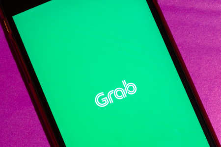 Los Angeles, California, USA - 22 January 2020: Grab App logo on phone screen flat lay with purple...