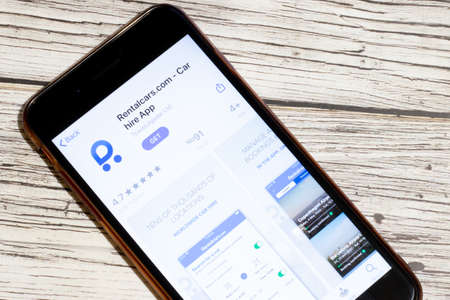 Los Angeles, California, USA - 25 January 2020: Logo of Rentalcars mobile app on phone screen close up top view on wooden table, Illustrative Editorial.のeditorial素材