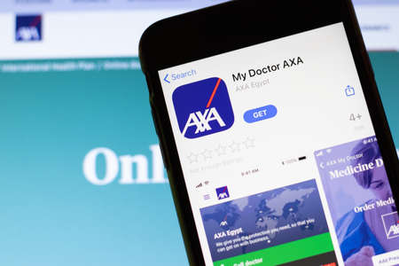Los Angeles, California, USA - 12 February 2020: Mobile phone with My Doctor AXA icon on screen close up with website on laptop. Blurred background with AXA site, Illustrative Editorial.のeditorial素材
