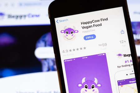 Los Angeles, California, USA - 12 February 2020: Mobile phone with HappyCow icon on screen close up with website on laptop, Illustrative Editorial.のeditorial素材