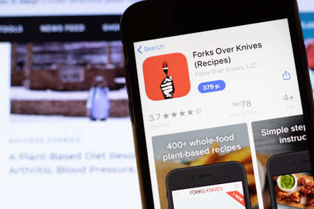 Los Angeles, California, USA - 12 February 2020: Mobile phone with Forks Over Knives icon on screen close up with website on laptop, Illustrative Editorial.のeditorial素材