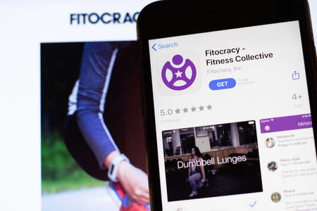 Los Angeles, California, USA - 12 February 2020: Mobile phone with Fitocracy icon on screen close up with website on laptop. Blurred background with Fitocracy.com site, Illustrative Editorial.のeditorial素材