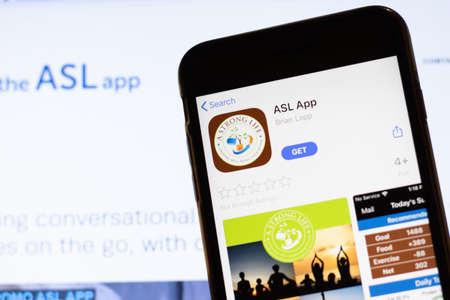 Los Angeles, California, USA - 12 February 2020: Mobile phone with ASL App icon on screen close up with website on laptop. Blurred background with TheAslApp.com site, Illustrative Editorial.のeditorial素材