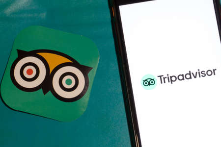 Los Angeles, California, USA - 12 February 2020: TripAdvisor app logo and phone with icon close up , Illustrative Editorial.のeditorial素材