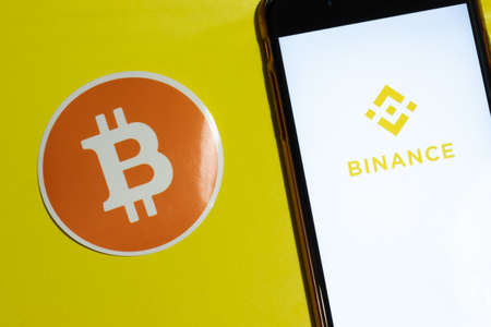 Los Angeles, California, USA - 12 February 2020: Binance app logo and phone with bitcoin icon close up , Illustrative Editorial.のeditorial素材