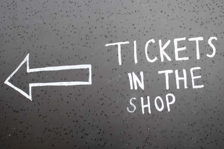 The inscription Tickets in the Shop with a left arrow. Chalk inscription on blackboard with pointer.の写真素材