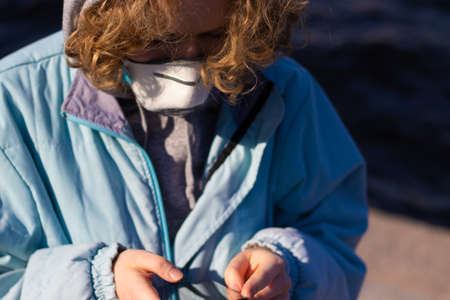 Close up shot of girl using her phone. Young woman wears a medical mask to protect the respiratory...