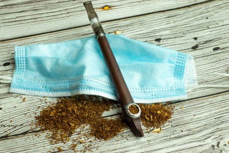 Smoking pipe accessory with tobacco and medical mask top view.の写真素材