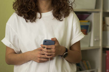 Modern business woman with phone in hands and oversize shirt in office. Copy space.